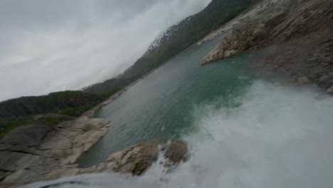 voo aéreo sobre o lago fjellhaugvatnet cercado por cachoeiras, piscinas e árvores de montanhas na noruega