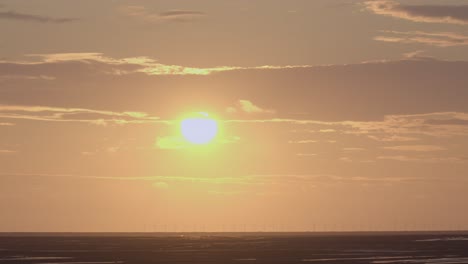 Die-Untergehende-Sonne-Bewegt-Sich-Hinter-Einer-Wolke-Und-Dann-Hinter-Einer-Anderen,-Während-Die-Silhouette-Der-Fähre-Am-Horizont-Vorbeizieht