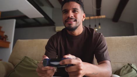 cheerful ethnic man playing video game on bed