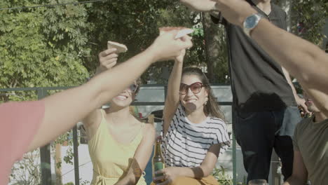 happy men and women raising slices of pizza during outdoor party