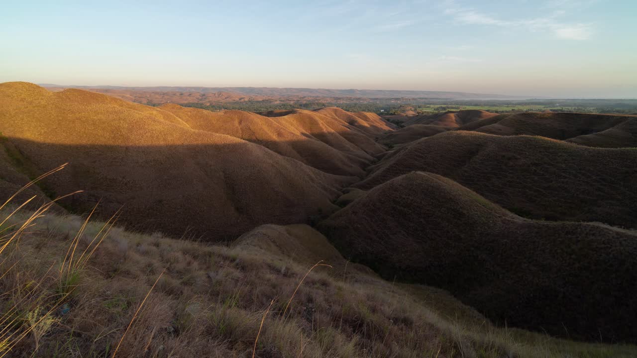 Vasto paesaggio di dolci colline erbose e aride all'alba o al tramonto
