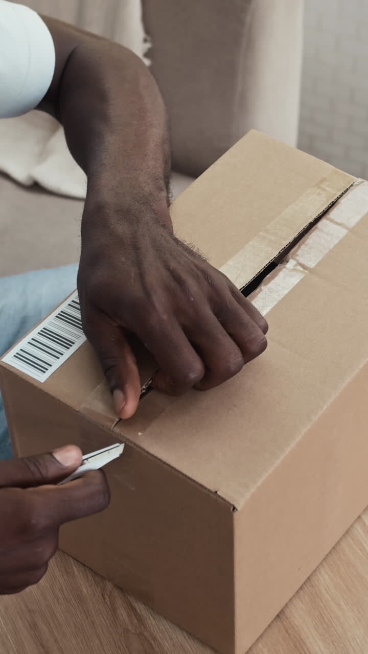 Uomo che apre un pacco consegnato a casa sua