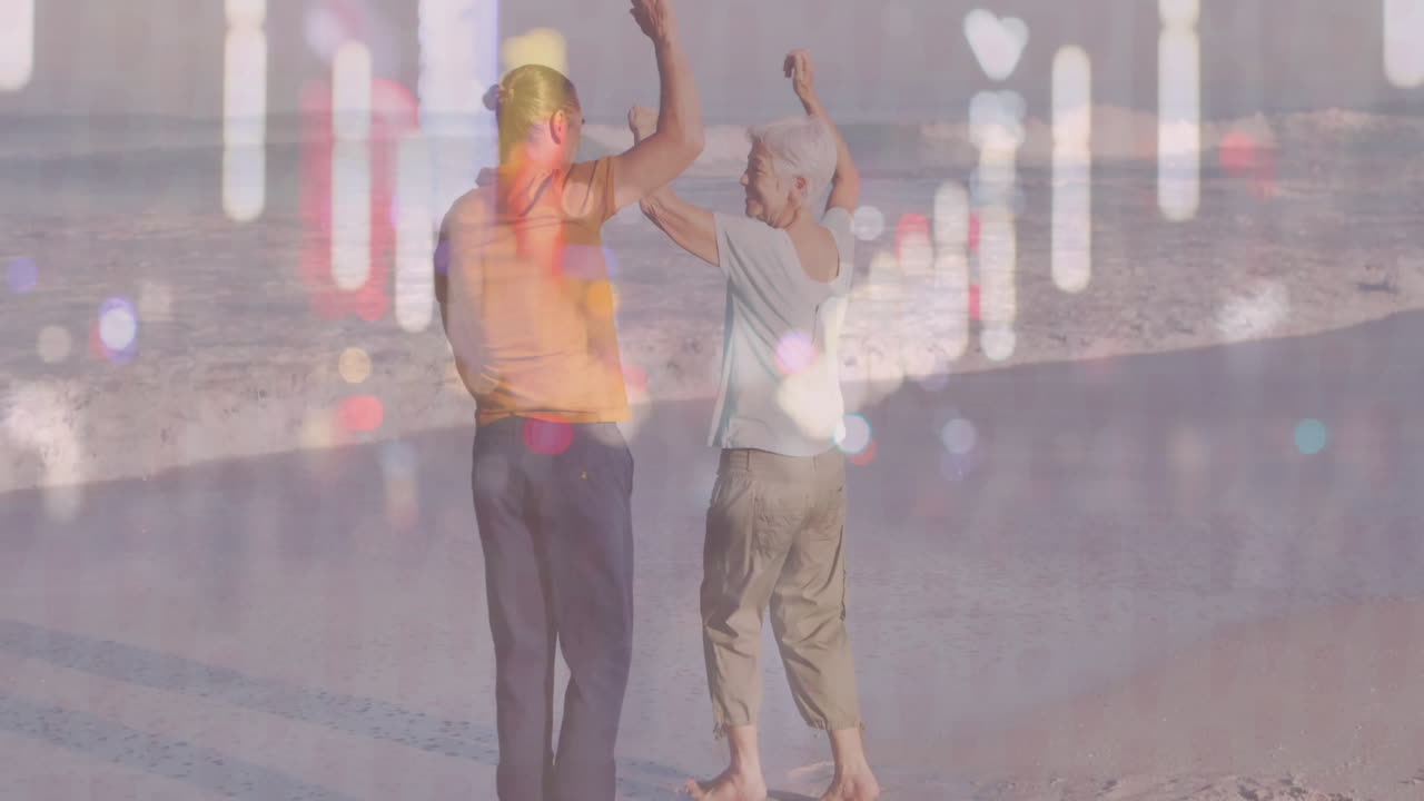 Mature man and senior woman dancing barefoot on beach, overlaying health charts and sun icons