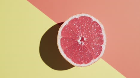 video of sliced red grapefruit with copy space over orange and yellow background