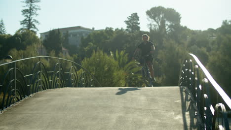 long shot of man with artificial leg riding bicycle in park