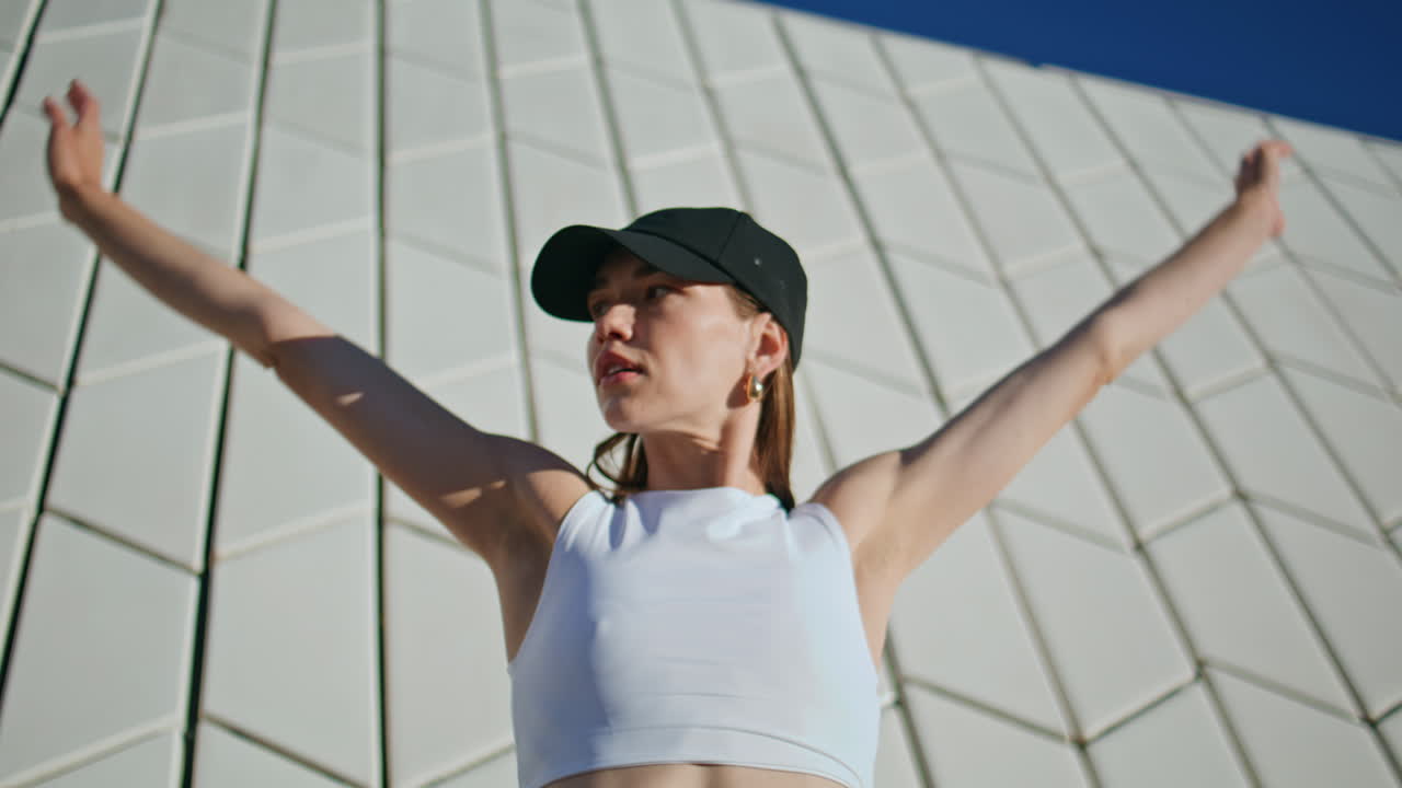 Pilates woman raising hands practicing physical activity on sunny street closeup