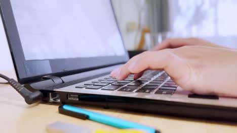 side view of a woman's hands on a laptop keyboard, engaged in online work or communication