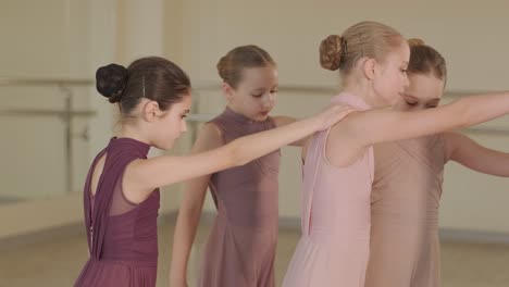 a group of young ballet students in black dancewear practicing positions in a spacious ballet studio with wooden flooring and wall-mounted barres. focused expressions and synchronized movements.