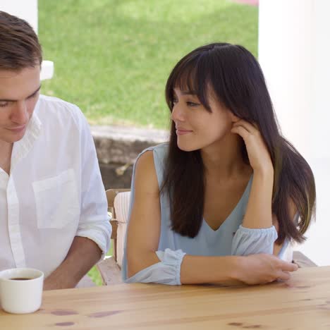 Happy-young-mixed-couple-sitting-at-table