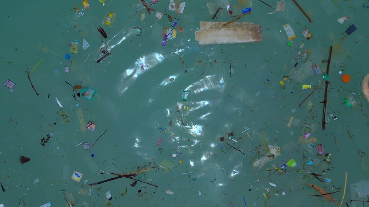 Agua cristalina turquesa del océano y playa de arena contaminada con residuos plásticos, escombros y basura marina. Concepto de crisis ambiental. Magnífica vista aérea de cámara de dron apuntando hacia abajo.