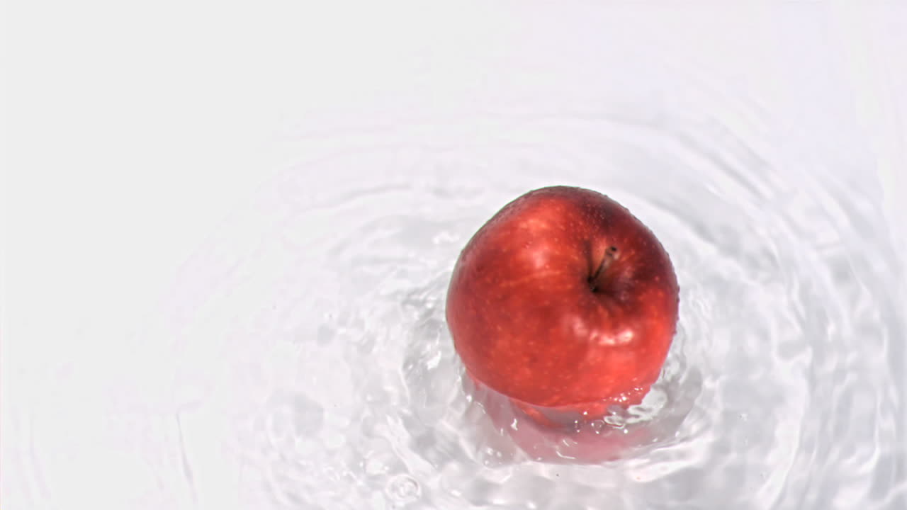 manzana girando en el agua en super cámara lenta