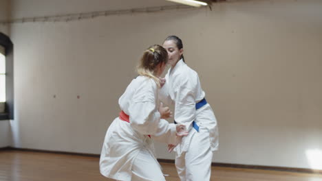 long shot of focused girls practicing karate movements in gym