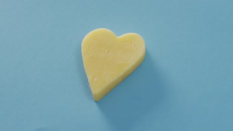 Video-of-heart-shape-of-cheese-on-blue-background-with-copy-space