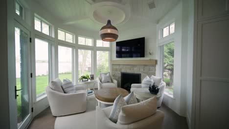 cozy circular hearth room with white chairs, natural light windows, and television