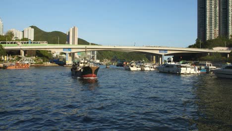 toma de un barco que pasa por un entorno urbano con un puente cerca de una ciudad costera al final de la tarde