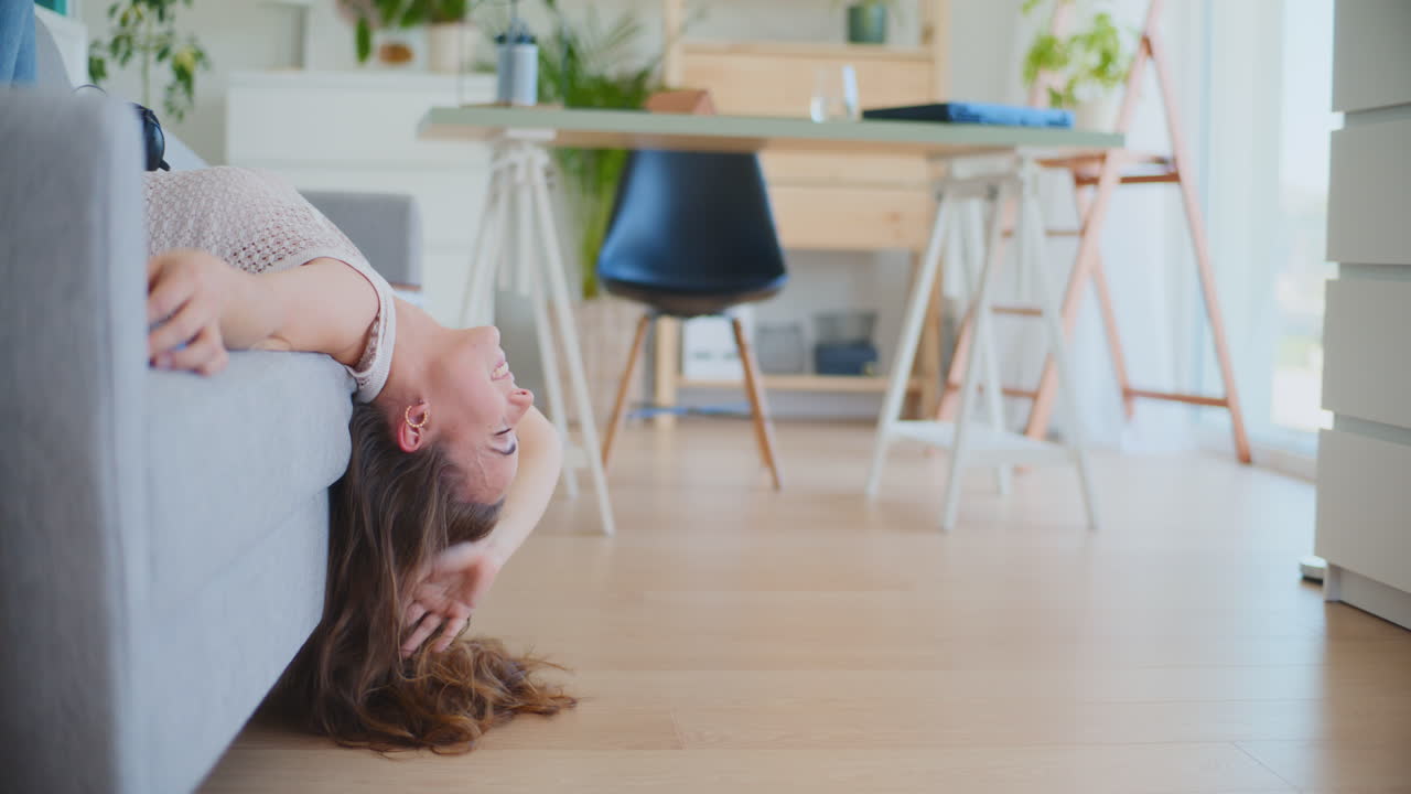 Woman Lays Upside Down on Sofa Reading Book