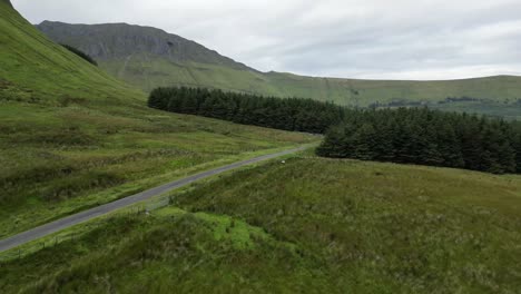 Drone-shot-flying-over-the-Irish-farmland-and-a-road-with-Glenniff-Horseshoe-in-the-background