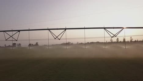 aerial pan of pivot irrigation efficiently watering crop at sunset
