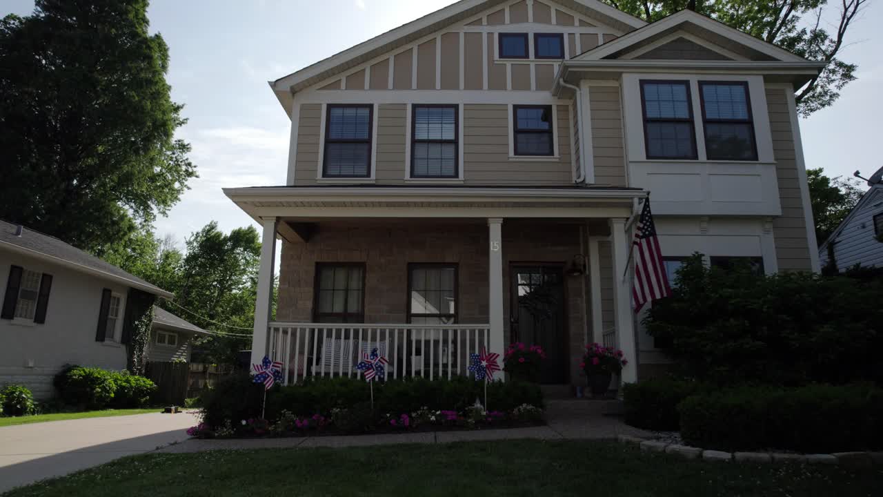 alejarse de una bonita casa de clase media con bandera estadounidense y decoraciones patrióticas en un día soleado de verano