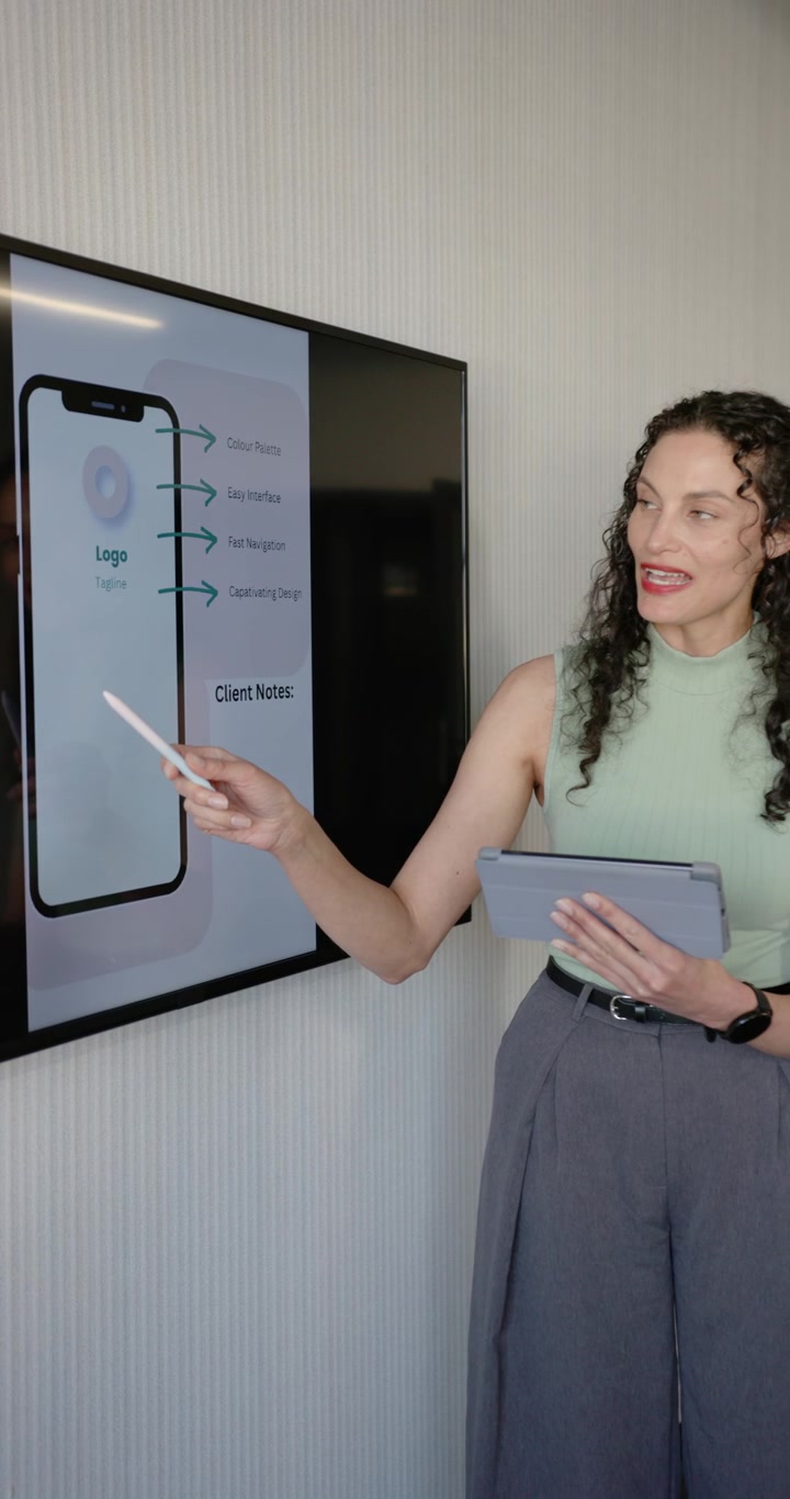 Video verticale: Donna afroamericana che interagisce con un mockup di telefono, indicando con un puntatore, leggendo un tablet