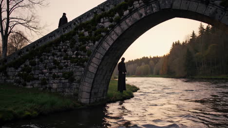 man standing under an ancient stone bridge at sunset