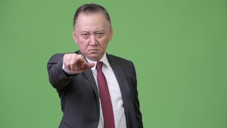 mature angry japanese businessman pointing at camera