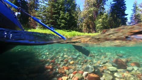 a shot, showing under and above the water at the same time, of a raft floating down a river