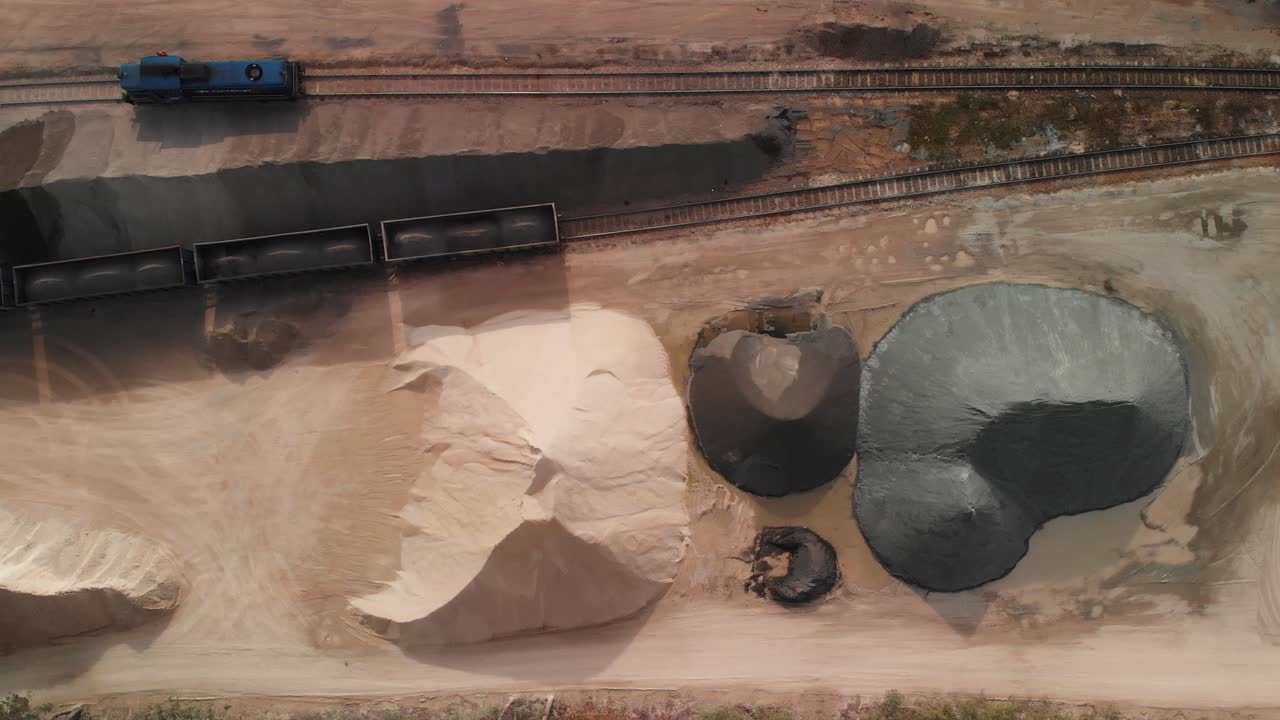 Aerial top down shot of a big stacks of sand and gravel and trains standing in a rail gravel terminal