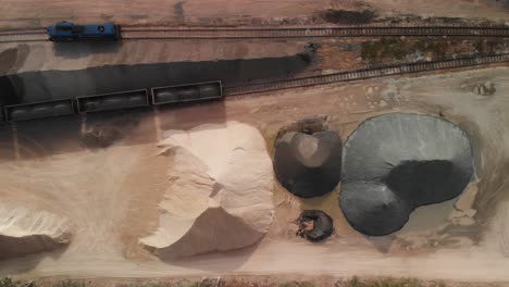 aerial top down shot of a big stacks of sand and gravel and trains standing in a rail gravel terminal