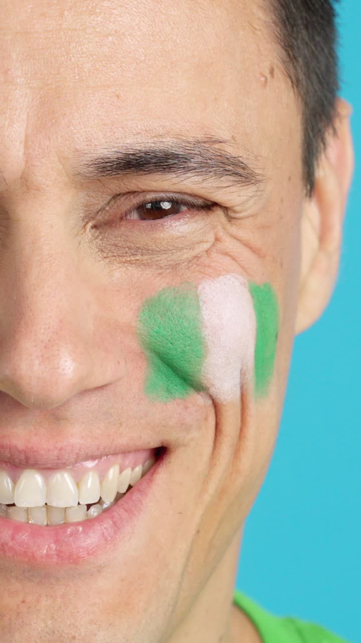 Man with a nigerian flag painted on the face smiling