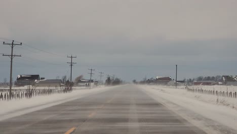 POV-Driving-Through-Owen-Sound-Along-Empty-Road-With-Windy-Snow-Drift-Blowing-Across-Road-Causing-Visibility-Hazard