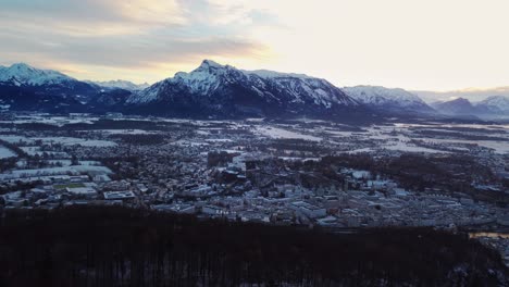 salzburg snow covered cityscape, sideways, establishing with alps behind