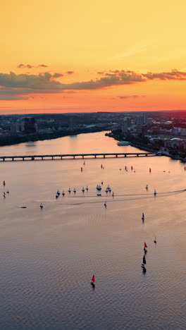Flying above the Charles River in Boston. Splendid cityscape and waterscape in orange rays of sundown.. Vertical video