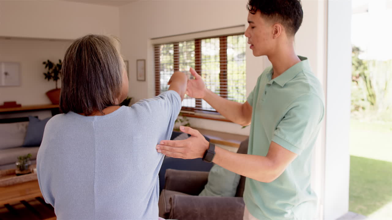 Helping senior woman with arm exercises, male physiotherapist guiding movements