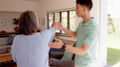 helping senior woman with arm exercises, male physiotherapist guiding movements
