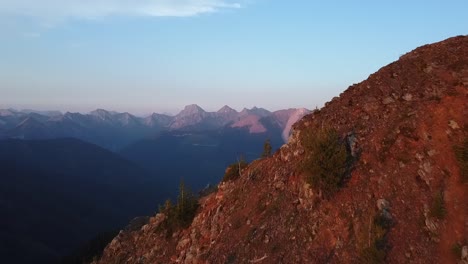 golden hour light covering the mountain, aerial shot with background reveal
