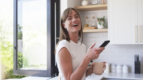 Middle-aged-Caucasian-woman-smiles-in-a-bright-kitchen