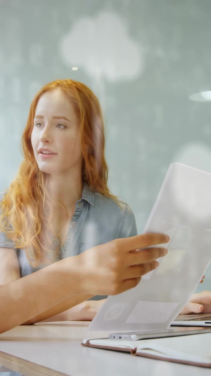 Video verticale: Donna che prende un documento da un collega per revisione, leggendo e indicando, con pin a forma di nuvola in movimento.