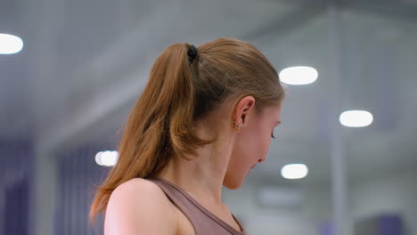 close-up of young woman working out, hand on knee in deep stretch exercise, with soft bokeh ceiling lights, focus on posture, flexibility, and toned physique in a serene fitness environment