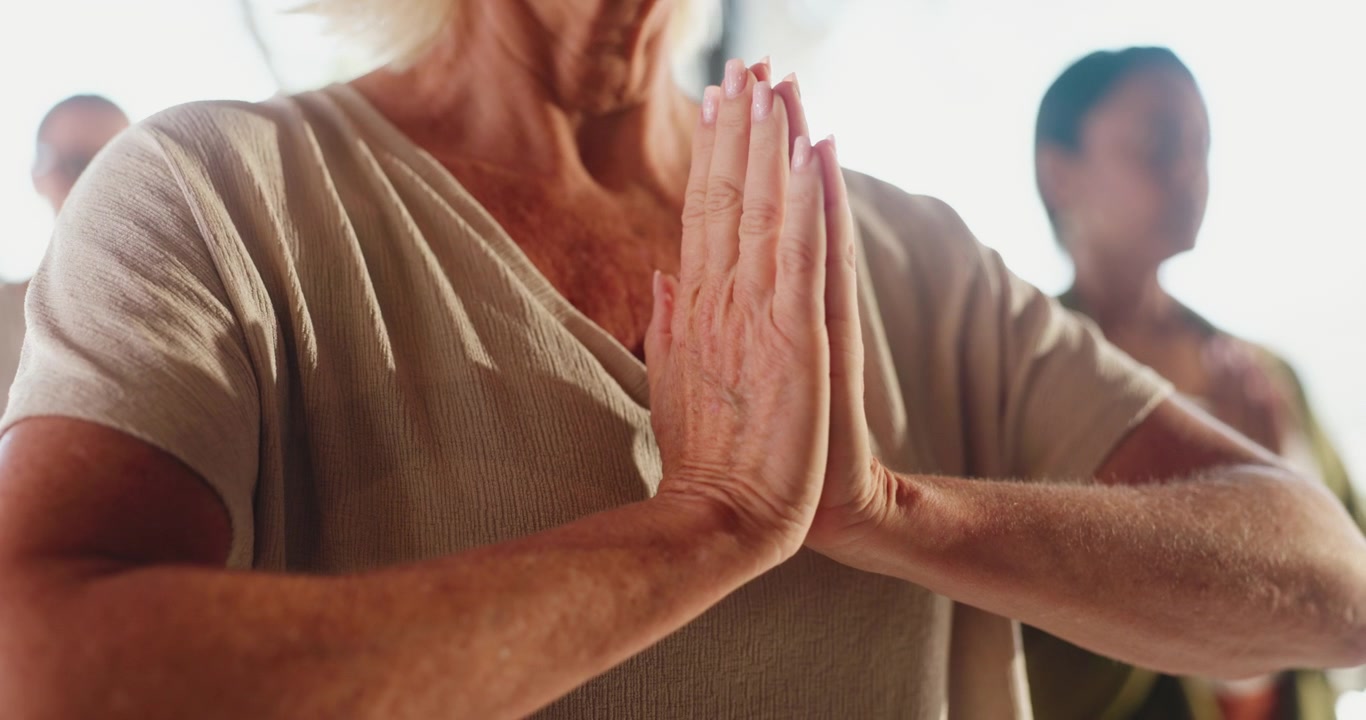 Donna anziana che pratica yoga con le mani in posizione di preghiera