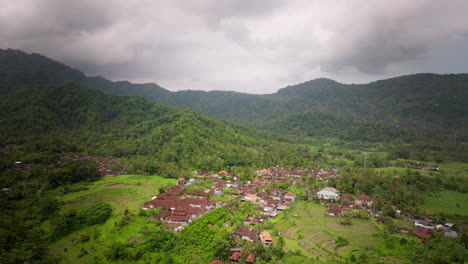 aerial dolly establishes red roof homes at toe slope of tropical mountain in bali