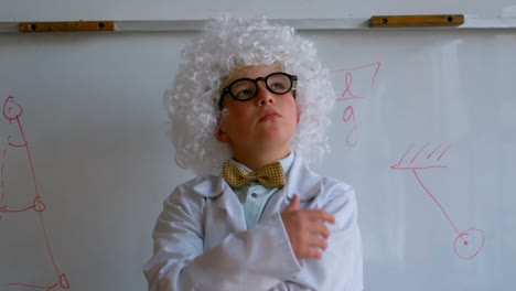 cute caucasian schoolboy in white wig with hand on chin standing in school laboratory 4k