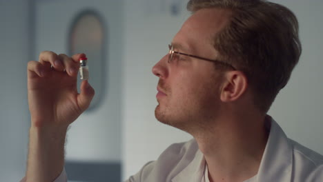 médico examinando el vial de vacuna de cerca. médico considerando el vial con vacuna.