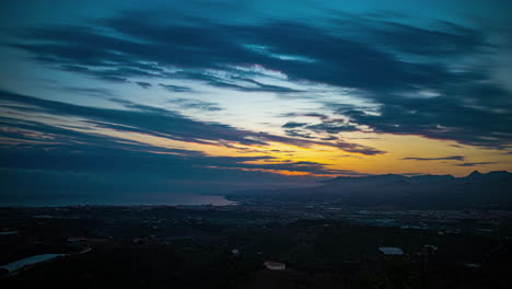 It-is-an-interesting-and-breathtaking-time-lapse-landscape,-showcasing-clouds-gracefully-moving-over-the-town-of-Malaga,-Spain,-in-the-evening