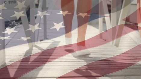 American-flag-waving-against-low-section-of-caucasian-woman-walking-on-wooden-pier