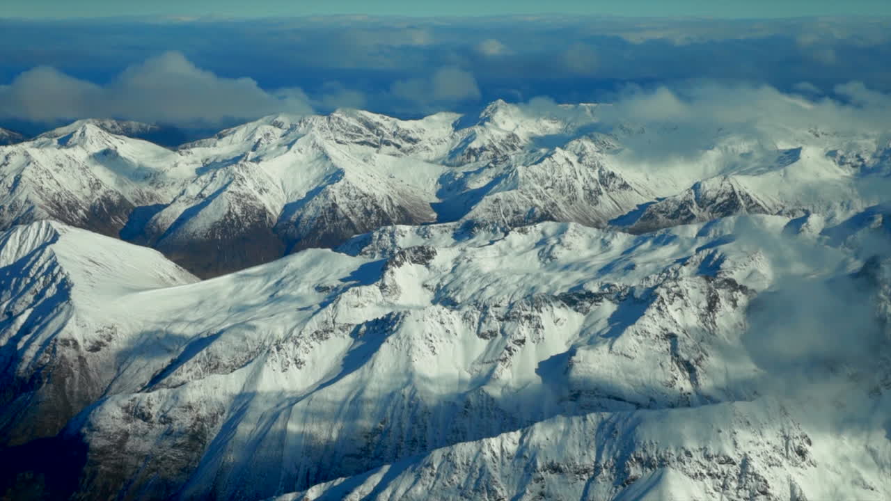 las cimas nevadas de las montañas de la isla sur de queenstown nueva zealandia vuelo aéreo de drones a gran altitud invierno nublado hermosa mañana soleada tarde lago wanaka wakatipu paisaje movimiento a la izquierda