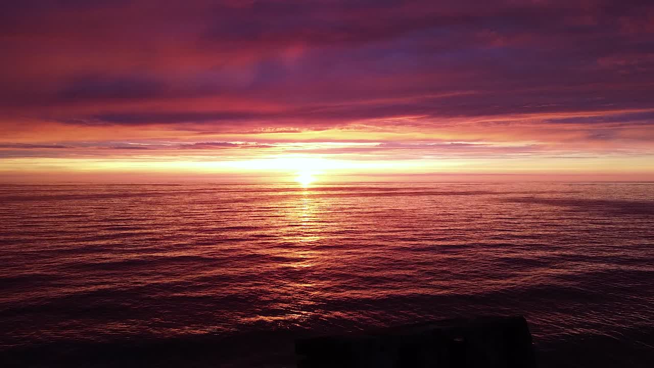 발트해의 아름다운 공중 생생한 고대비 분홍색 보라색 일몰, 카로스타 전쟁 항구 콘크리트 해안 요새 폐허 리파자, 광각 드론 샷 뒤로 이동