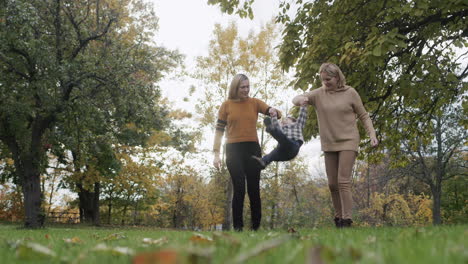 two young women walking with a toddler in the park, having a good time together