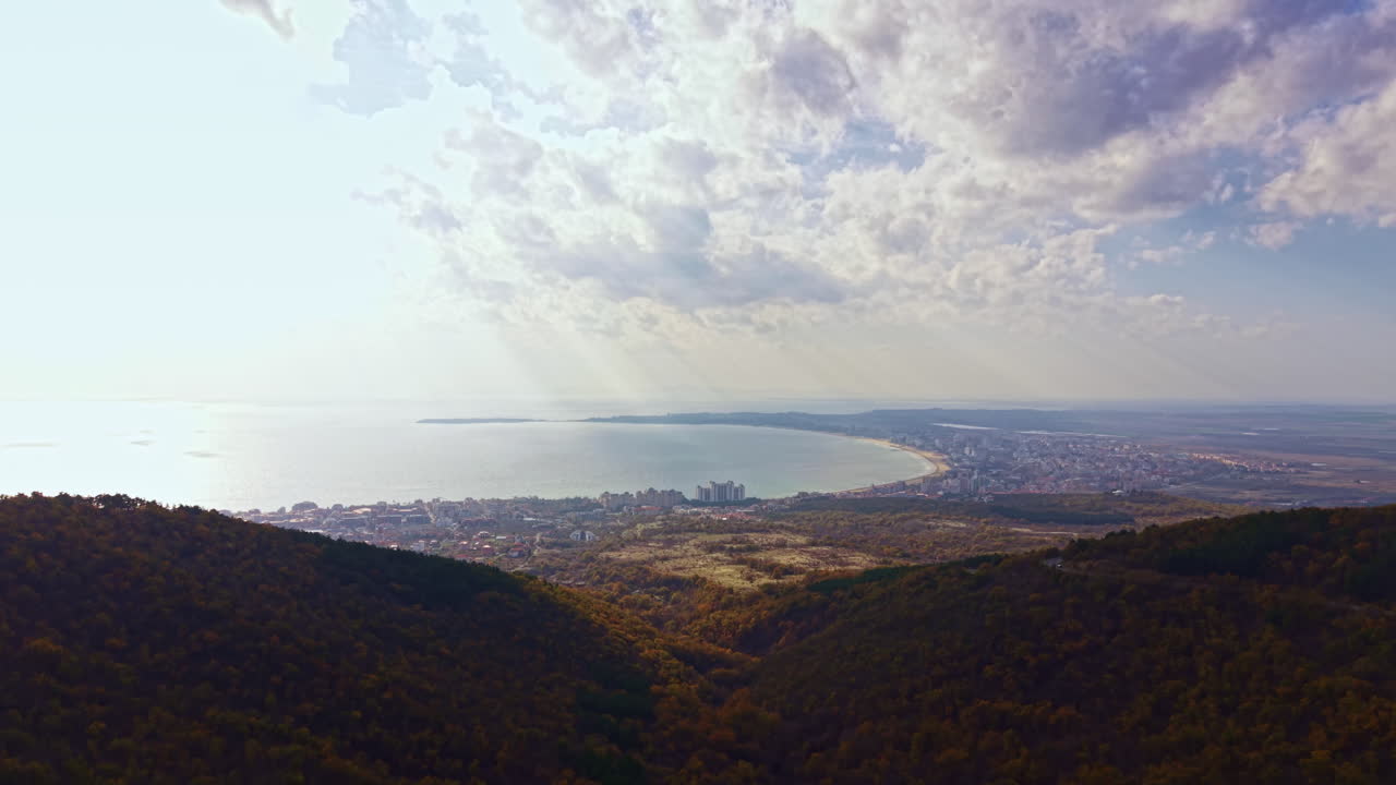 Panorama costiero che mostra una baia soleggiata, una città in lontananza e un cielo nuvoloso, catturando la bellezza della natura e della vita costiera in Bulgaria