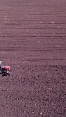 shooting from drone flying over tractor with harrow system